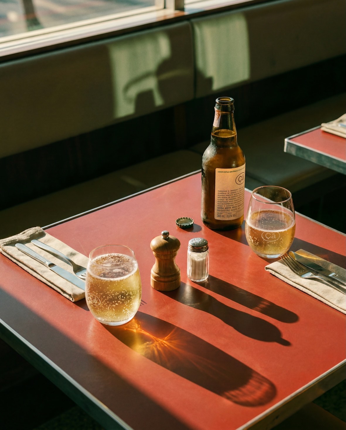 Garrafa de sidra Çã sobre mesa de restaurante, luz de fim de tarde